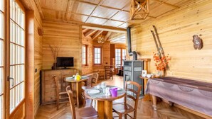 Uma cabana de madeira acolhedora com área de jantar, cozinha com fogão e televisão.