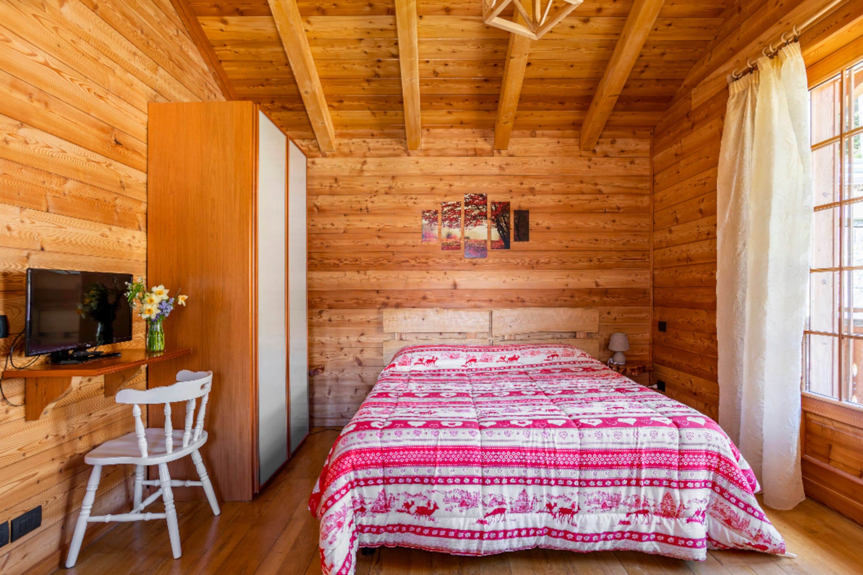 Ein Zimmer in einer Holzhütte mit einem Bett, einem Schreibtisch und einem Stuhl.