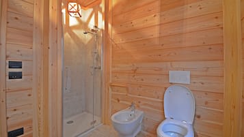 A wooden cabin bathroom with a shower, bidet, and toilet.