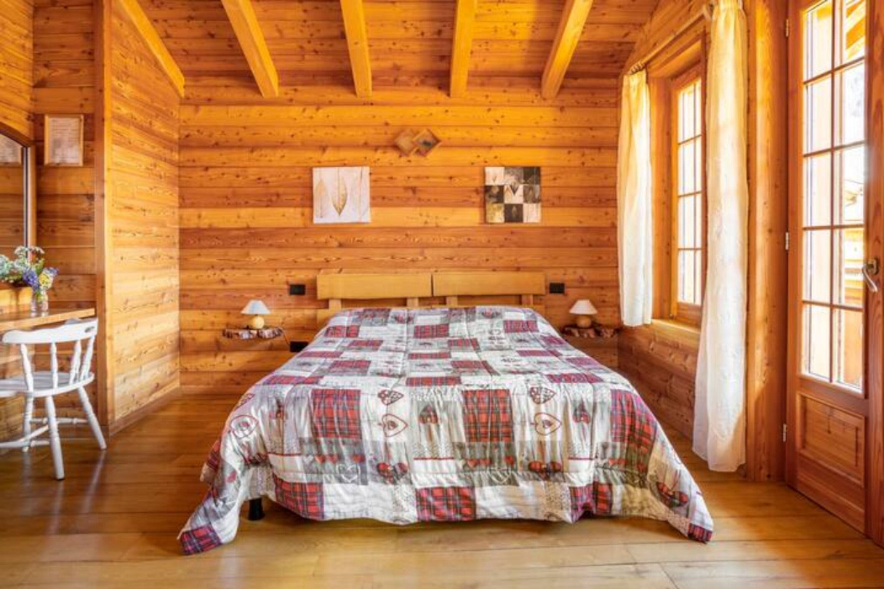 A log cabin room with a bed, a desk, and a chair.