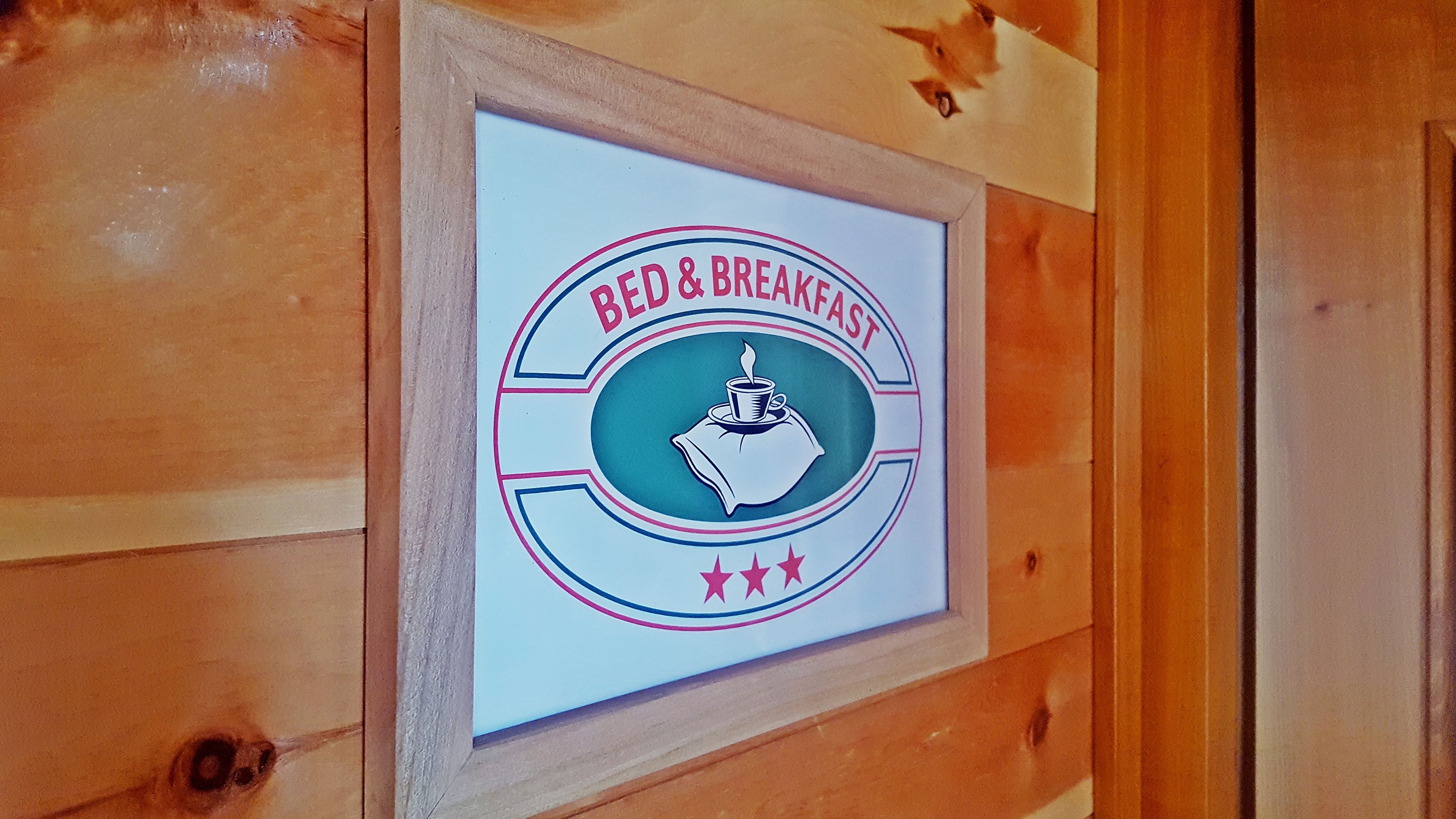 A framed sign with the text "BED & BREAKFAST" and a cup of coffee illustration.