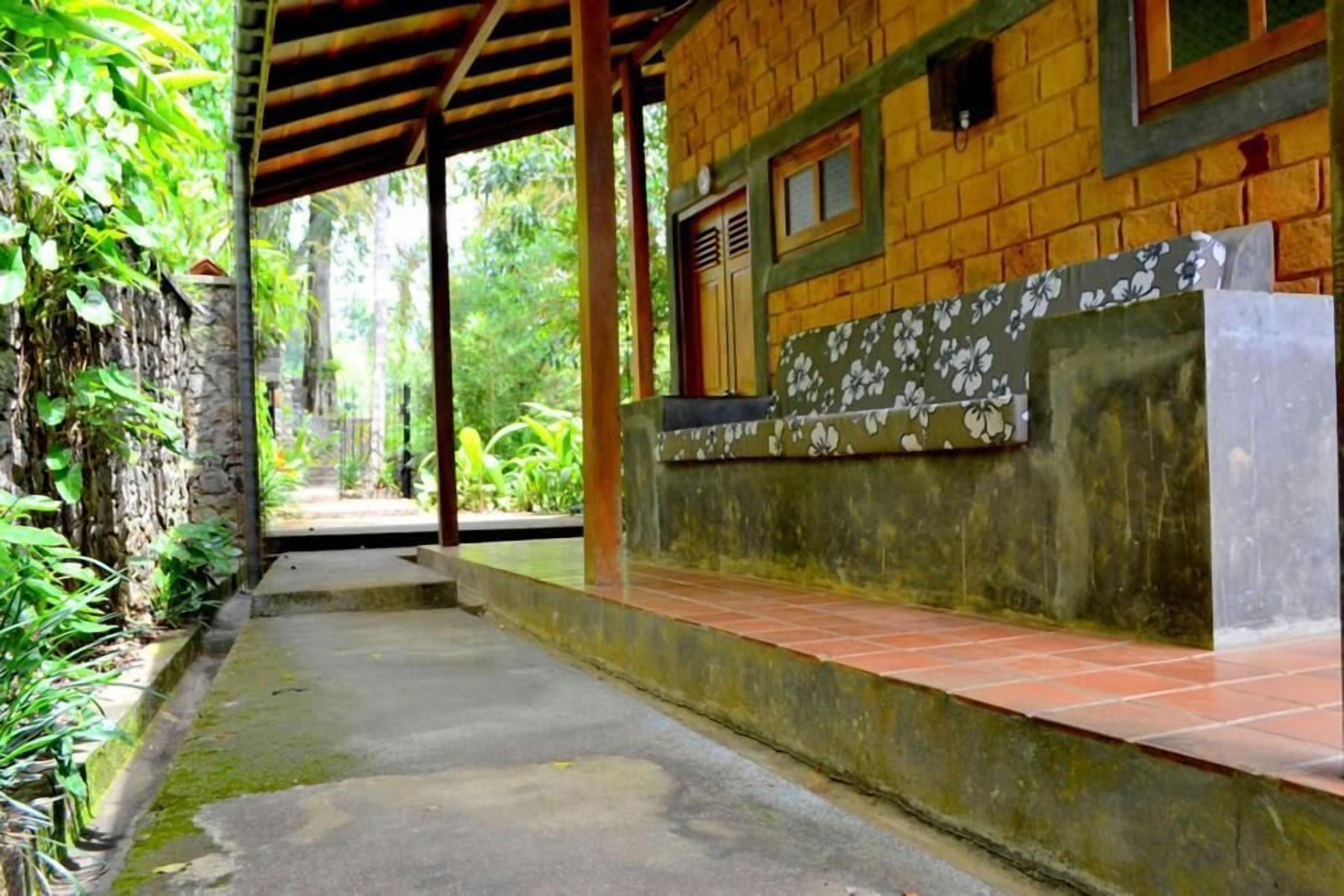 Un espacio al aire libre cubierto con un muro de piedra, una estructura de madera y una plataforma de baldosas.