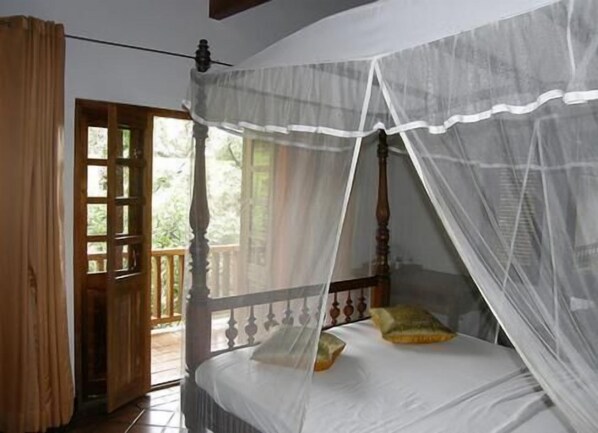 A bedroom with a four-poster bed, a wooden door, and a balcony. - Landa Holiday House (Imbulpe)