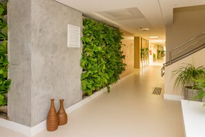Un couloir avec un mur en béton, des plantes vertes et deux vases.