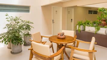 Un comedor moderno con sillas de madera y una mesa redonda, rodeado de plantas en macetas.