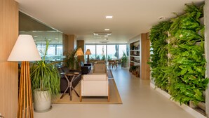 Ein modernes Interieur mit einer Couch, Sesseln, einem Esstisch und einer großen Kübelpflanze.