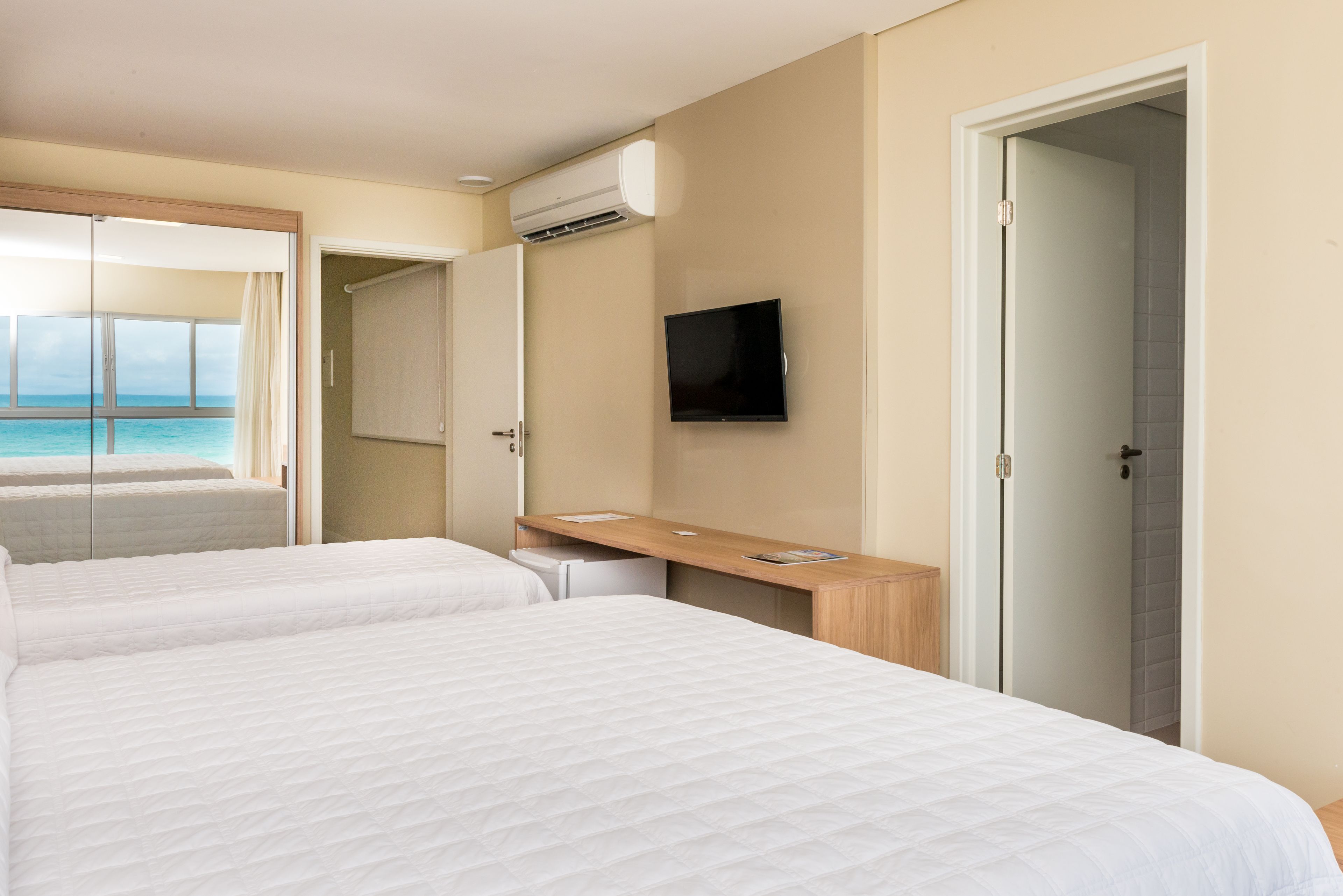Habitación de hotel con dos camas, televisión y vista al océano.