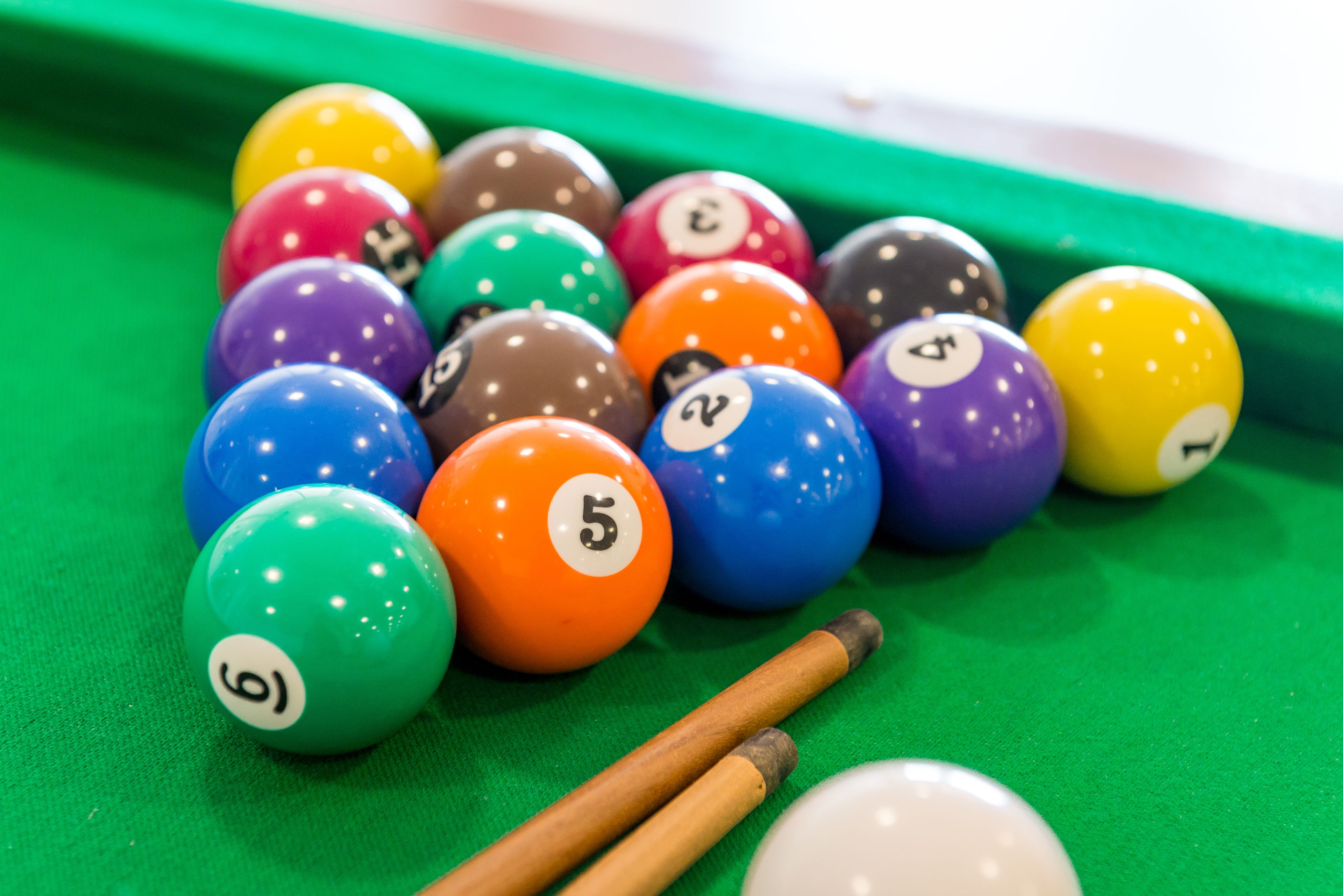 Une table de billard avec des billes de différentes couleurs et des queues de billard.
