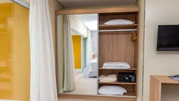 A hotel room with a wooden wardrobe, a bed, a television, and a mirror.