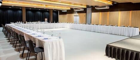 A conference room with a long table, chairs, and a stage.
