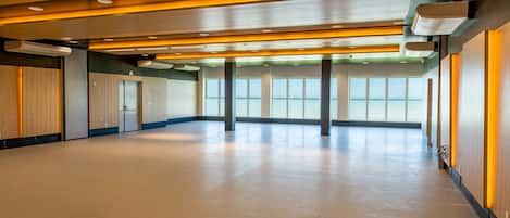 Un intérieur spacieux et moderne, avec un plafond haut, de grandes fenêtres et un sol en béton poli.
