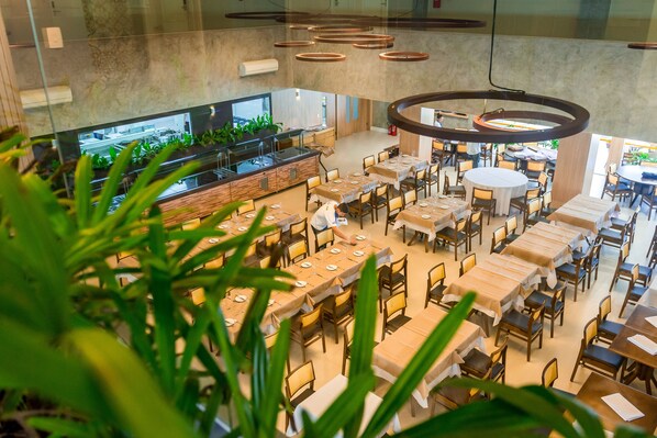 A spacious restaurant with multiple dining areas, a central bar, and a view of the kitchen.