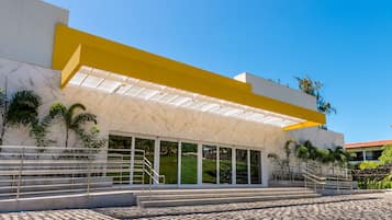 Un edificio moderno con un alero amarillo, ventanas amplias y una escalera que conduce a la entrada.