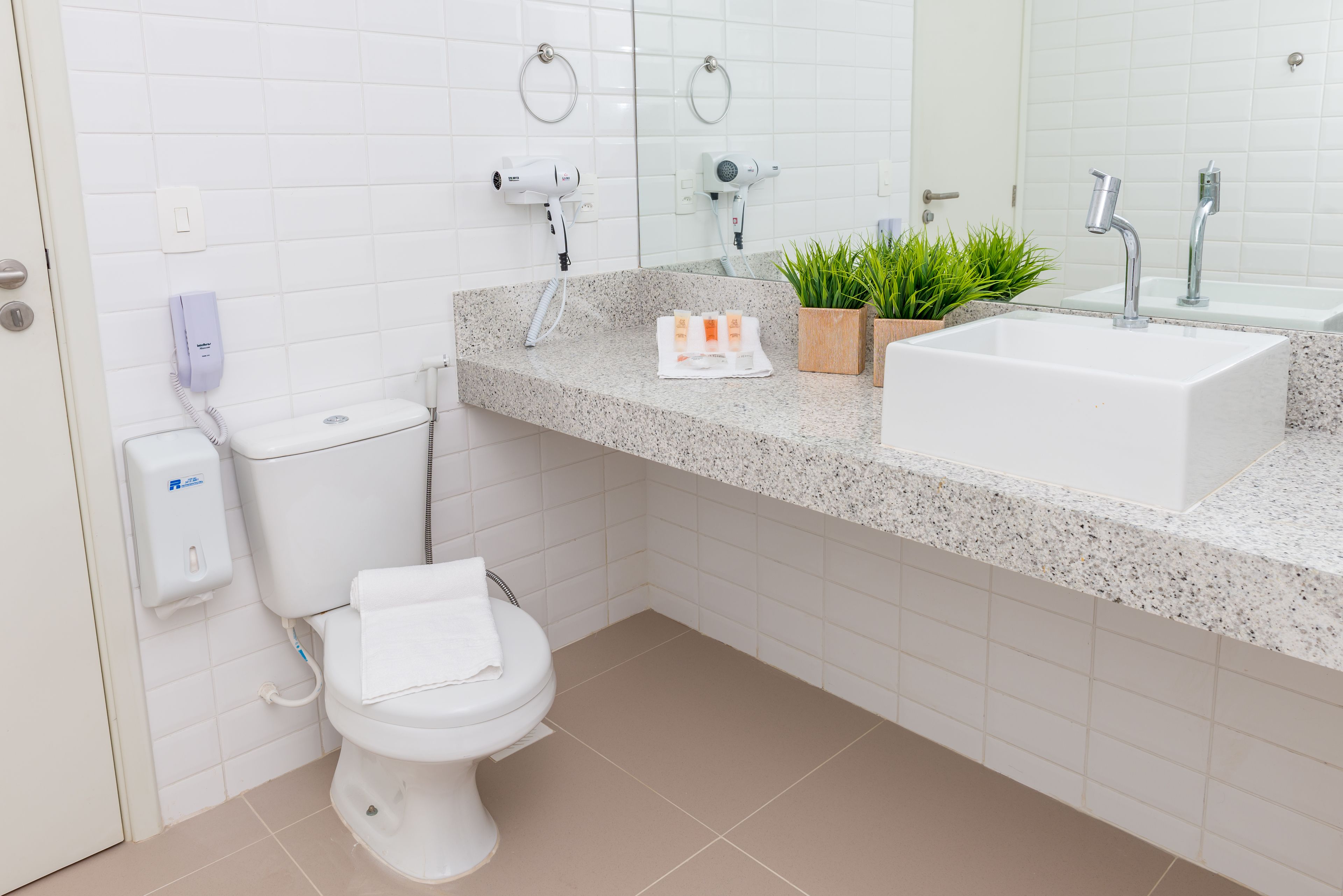 A modern bathroom with a toilet, sink, and hairdryer.