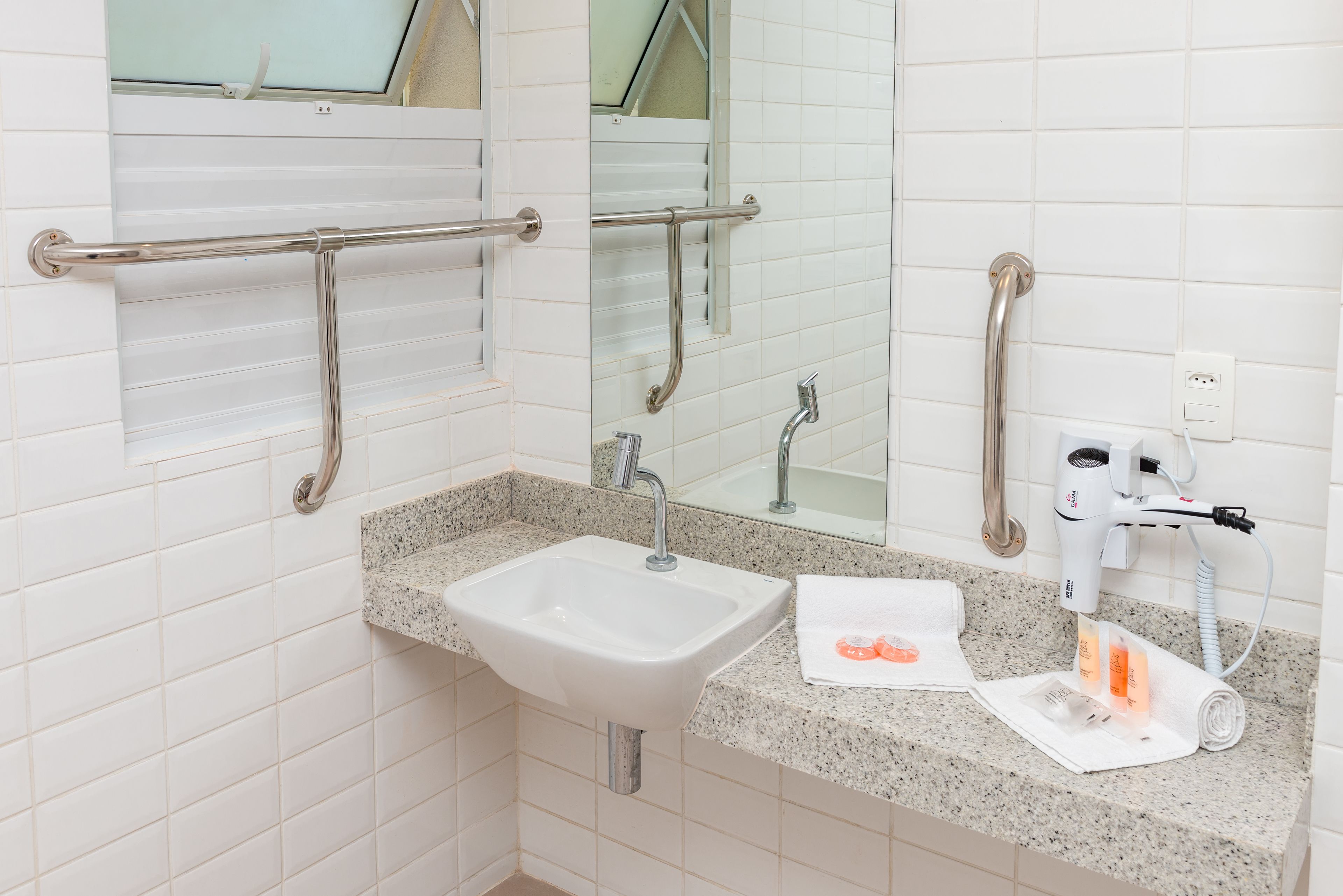 Un baño con lavabo, espejo, toallero y secador de pelo.