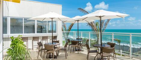 A terrace with outdoor seating and a view of the ocean.
