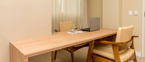 Una mesa de madera con dos sillas, una computadora portátil, una botella y un vaso.
