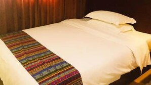 Ein Hotelzimmer mit einem Bett, einer farbenfrohen, gestreiften Decke und Holzvertäfelung an den Wänden.