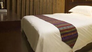 Ein Hotelzimmer mit einem großen Bett, dunklen Vorhängen und einer Wandpaneele aus Holz.