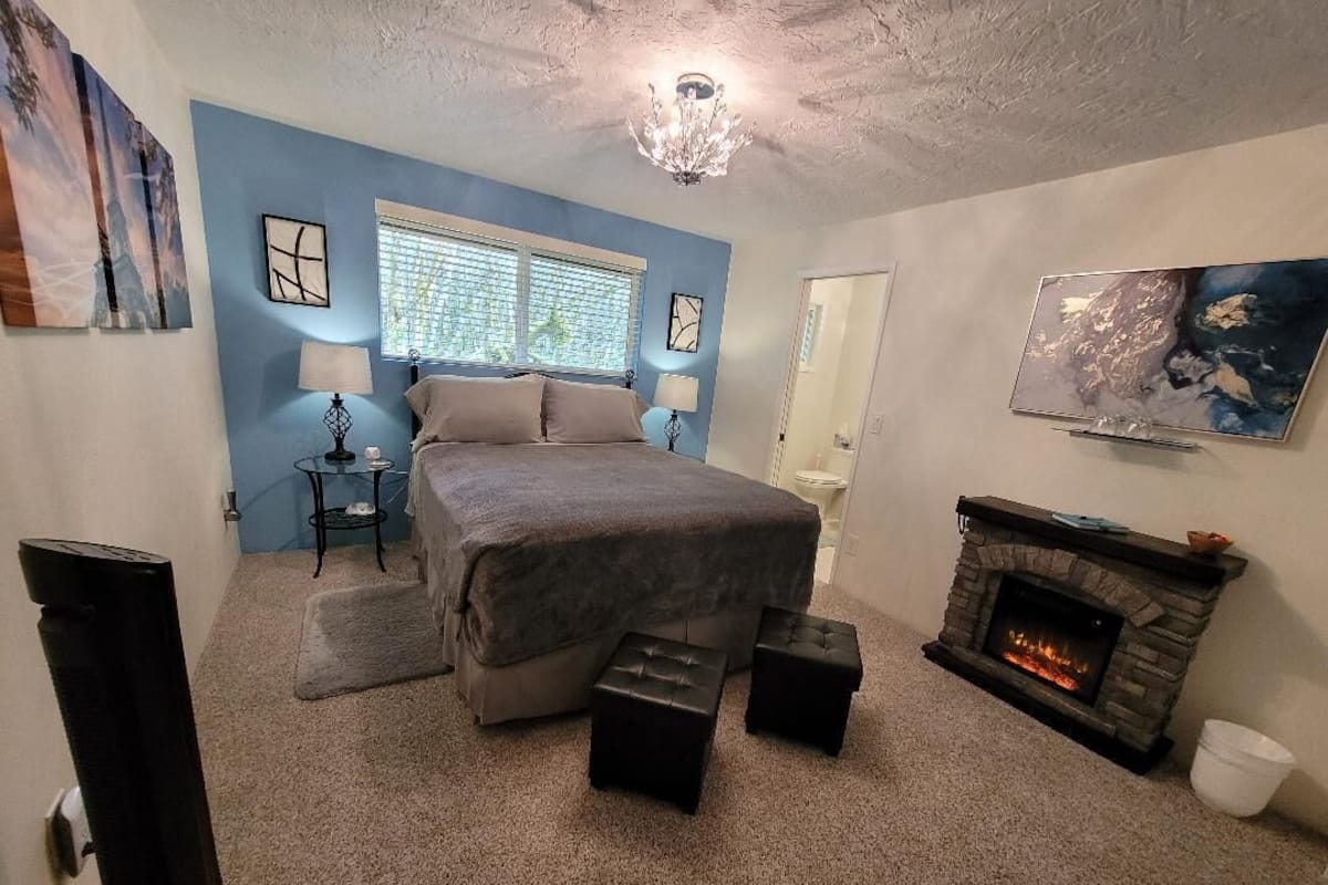 A bedroom with a bed, a fireplace, and artwork on the walls.