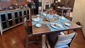 Un comedor con una mesa de madera dispuesta para cuatro personas, flanqueada por armarios y una pared de piedra.