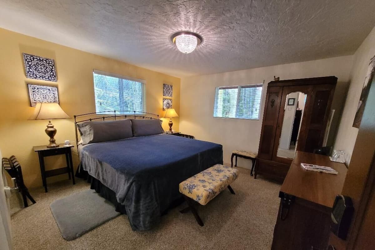 A bedroom with a bed, bedside tables, a bench, a dresser, and a mirror.