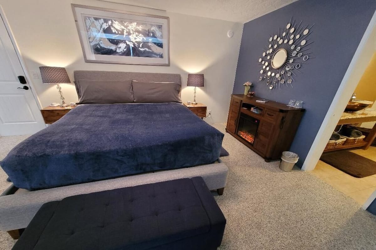 A bedroom with a bed, two bedside tables, a dresser, a mirror, and a picture on the wall.