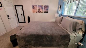 A bedroom with a bed, a nightstand, a lamp, and a window with blinds.
