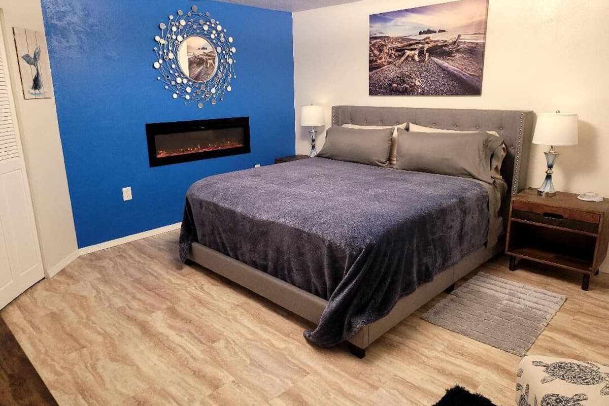 A bedroom with a bed, a wall-mounted TV, a nightstand, and a rug.