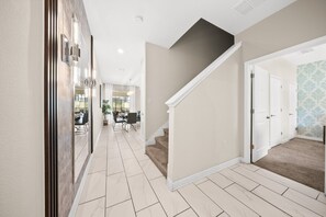 A hallway with a staircase leading to a dining area.