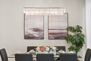 A dining area with a table set for four, two framed artworks above, and a potted plant to the side. - Poolside Bliss: Enchanted 4BR Townhome, Ultimate Fun! - 1556 (Davenport)