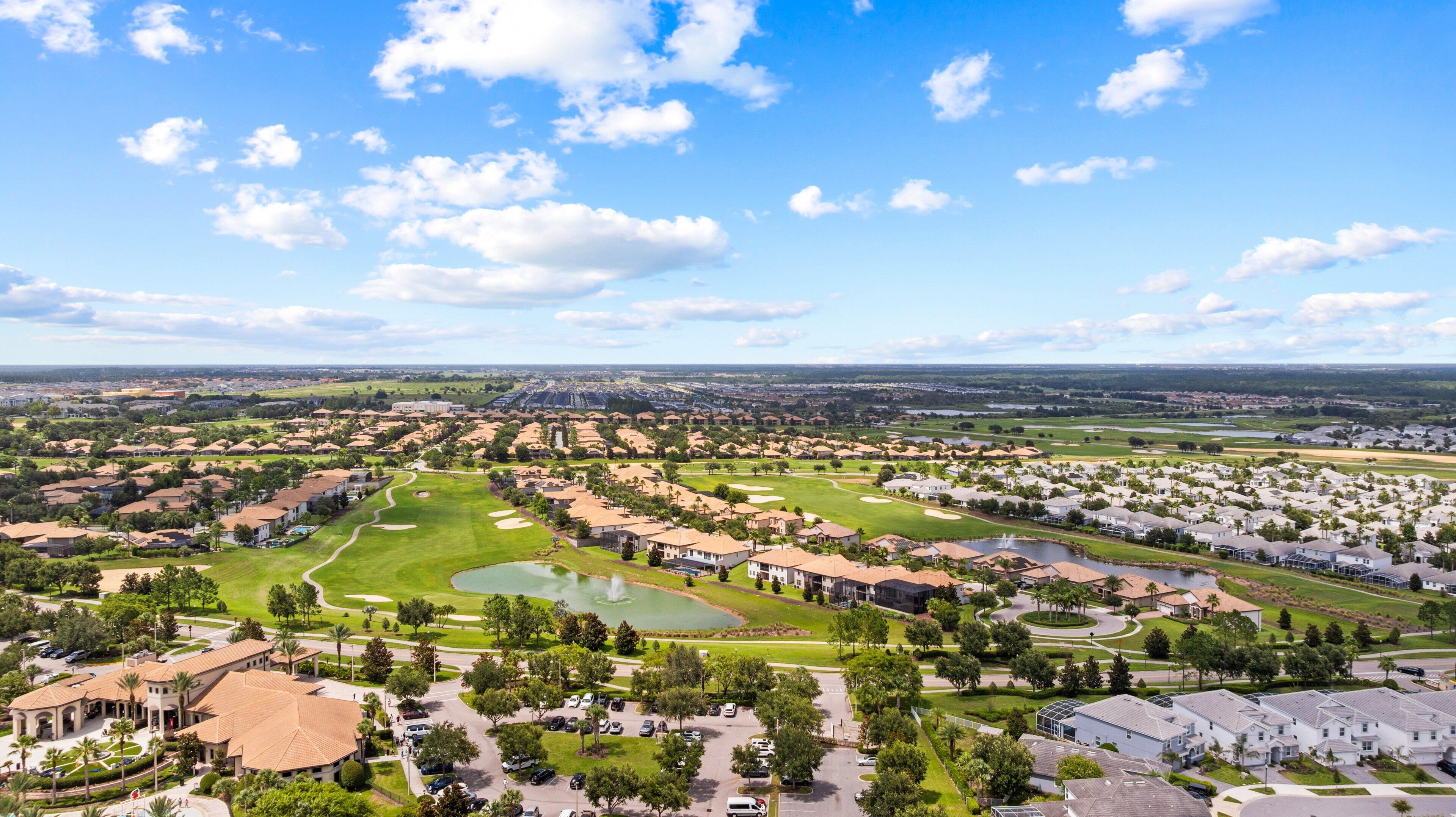 A residential area with houses, a golf course, and a large body of water.