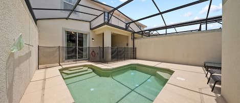 A swimming pool with steps leading into it, surrounded by a covered patio area with a glass ceiling.