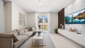 Ein modernes Wohnzimmer mit einem Ecksofa, einem Couchtisch und einem großen Flachbildfernseher an der Wand.
