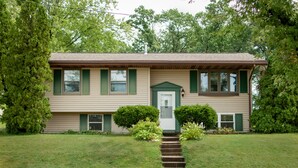 A two-story house with a front porch, a central door, and a small front yard.