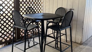 A covered patio area with a round table and four chairs.