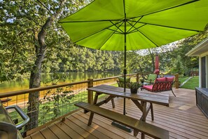Une terrasse en bois avec une table de pique-nique et des chaises, donnant sur un lac.