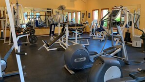 Ein Fitnessstudio mit verschiedenen Trainingsgeräten, darunter Laufbänder, Kraftgeräte und Kurzhanteln.