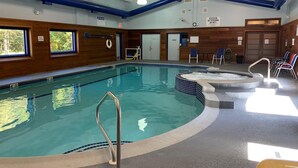 Ein Hallenbad mit Whirlpool, Holzwänden und einer Decke mit blauen und weißen Balken.