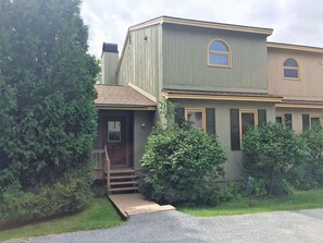 A two-story house with a front porch, a small front yard, and a driveway.