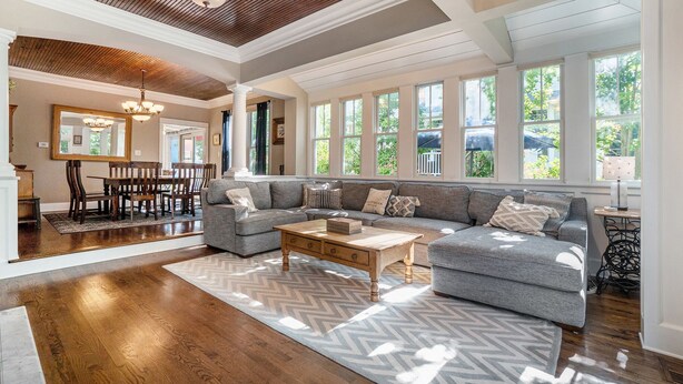 A spacious living room with a large sectional sofa, wooden coffee table, and a dining area with a chandelier.
