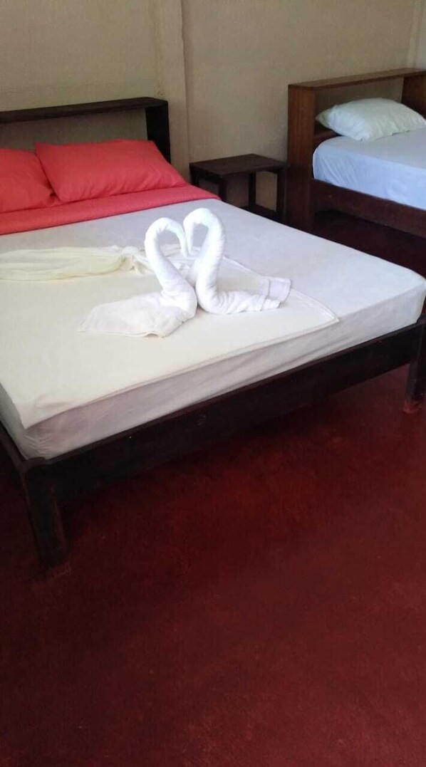 A bed with white linens and a towel arranged in a heart shape.