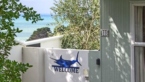 A 'WELCOME' sign with a shark silhouette on a building facade, overlooking a coastal view. - Castlepoint - Private family beach home with stunning views capturing the sun. (Castlepoint)