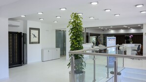 Um lobby moderno com escada, balcão de recepção e um relógio na parede.