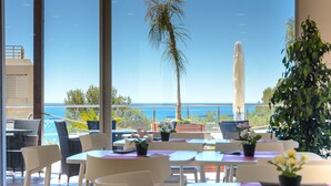 Restaurante com área externa, vista para uma piscina e para o mar.