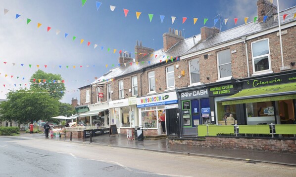 A street with shops, including a 24hr cash service and a bakery.