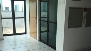 A spacious room with a tiled floor, a sliding glass door leading to an outdoor area, and a wall-mounted fire alarm.
