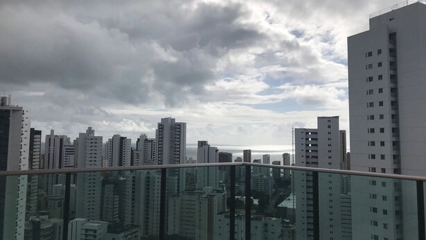 A high-rise building with a glass balcony overlooking a cityscape.