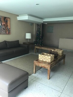 Una sala de estar con un sofá, una mesita de centro con cestas tejidas, una lámpara y un árbol de Navidad.