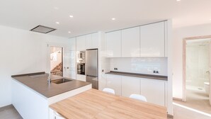 A modern kitchen with a central island, white cabinetry, and stainless steel appliances. - Holiday Apartment "Mirador" with Sea Views and Pool (Cala San Vicens)